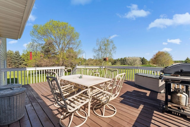 wooden deck featuring outdoor dining area, a yard, and area for grilling