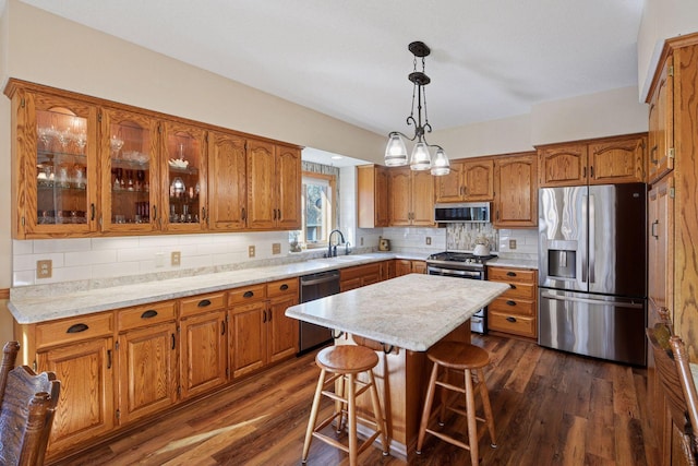 kitchen with appliances with stainless steel finishes, brown cabinets, light countertops, and a sink