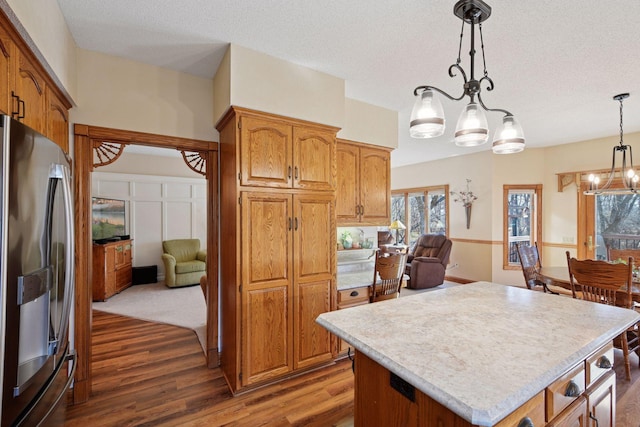 kitchen featuring stainless steel fridge with ice dispenser, a chandelier, light countertops, wood finished floors, and a textured ceiling