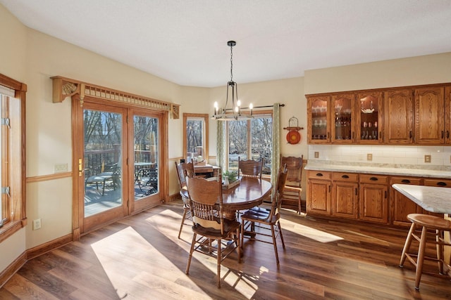 dining space featuring a chandelier, healthy amount of natural light, dark wood-type flooring, and baseboards