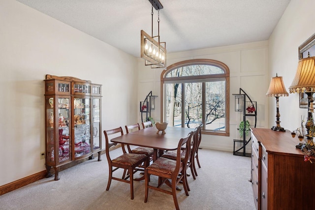 dining area featuring light carpet, baseboards, and a textured ceiling