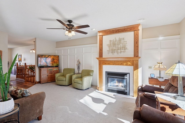 living room featuring ceiling fan, a large fireplace, and carpet floors