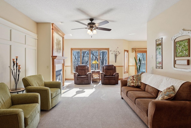 carpeted living area with ceiling fan, a glass covered fireplace, and a textured ceiling