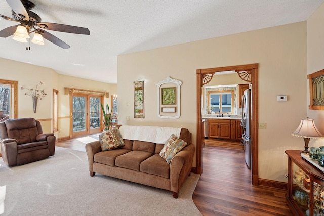 living room featuring a ceiling fan, dark wood-type flooring, and baseboards