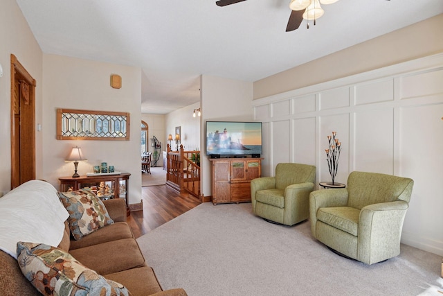 living area featuring ceiling fan, carpet floors, and wood finished floors