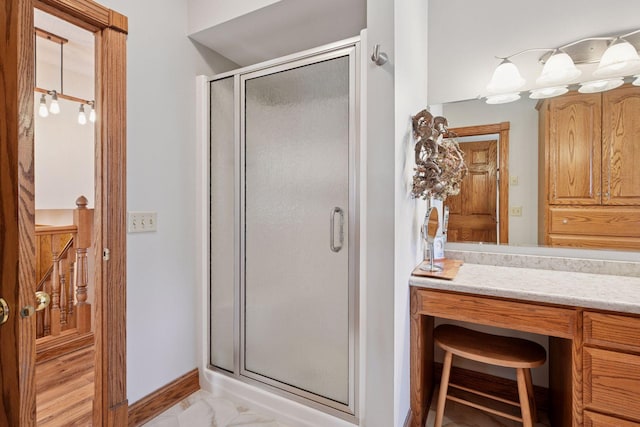 bathroom featuring a shower stall, marble look tile flooring, baseboards, and vanity