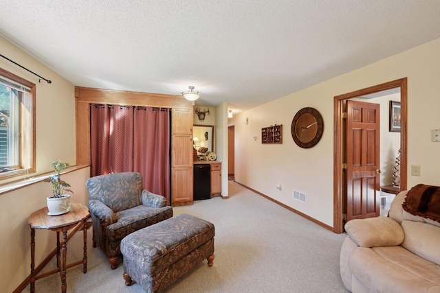 living area featuring light colored carpet, a textured ceiling, and baseboards