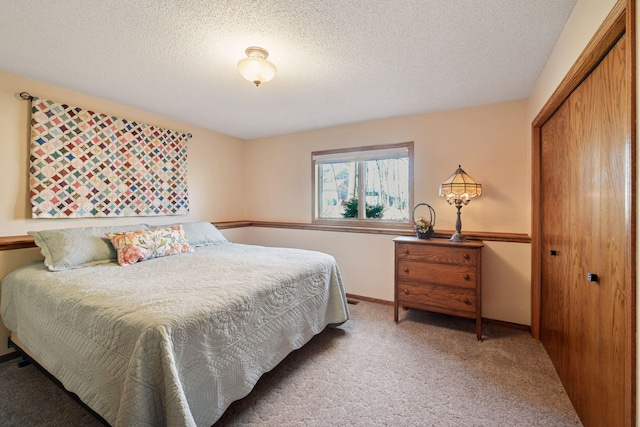 bedroom with carpet flooring, a closet, a textured ceiling, and baseboards