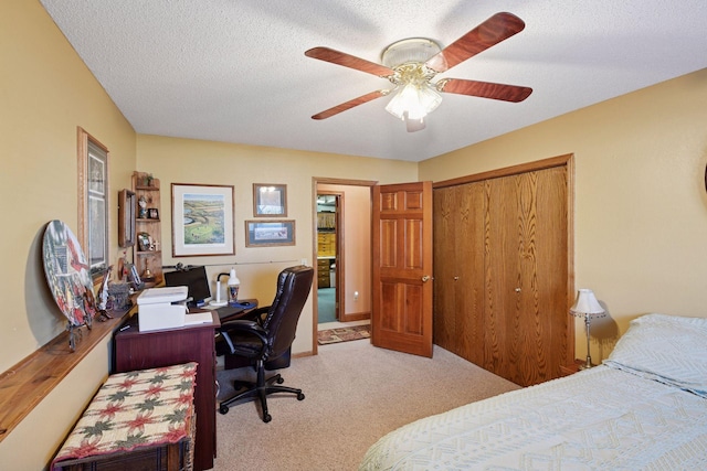 bedroom featuring carpet flooring, an office area, a closet, ceiling fan, and a textured ceiling
