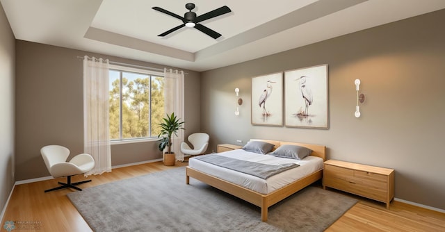 7854 Dogwood Dr, Horace, ND 58047 - bedroom featuring a tray ceiling, baseboards, light wood-style floors, and ceiling fan
