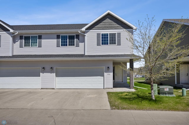 view of front of property with a garage, concrete driveway, a front lawn, and a shingled roof