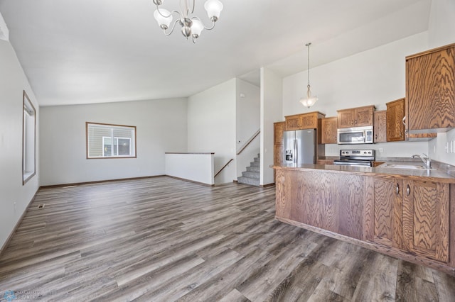 kitchen featuring appliances with stainless steel finishes, brown cabinetry, a sink, dark wood-style flooring, and pendant lighting