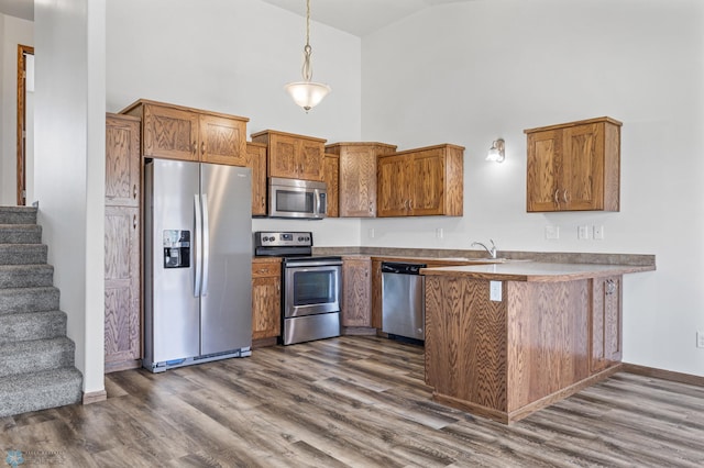 kitchen featuring stainless steel appliances, high vaulted ceiling, a peninsula, brown cabinetry, and dark wood-type flooring