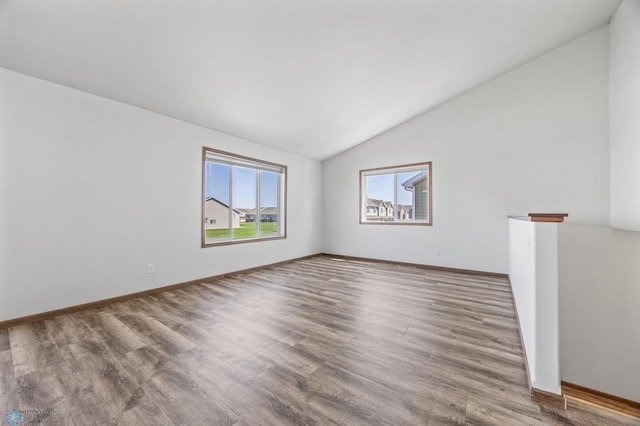 unfurnished room with lofted ceiling, wood finished floors, and baseboards