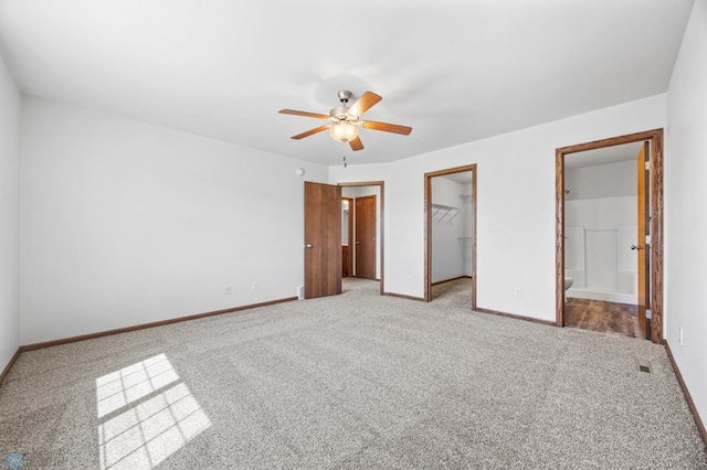 unfurnished bedroom featuring carpet flooring, a spacious closet, baseboards, a closet, and connected bathroom