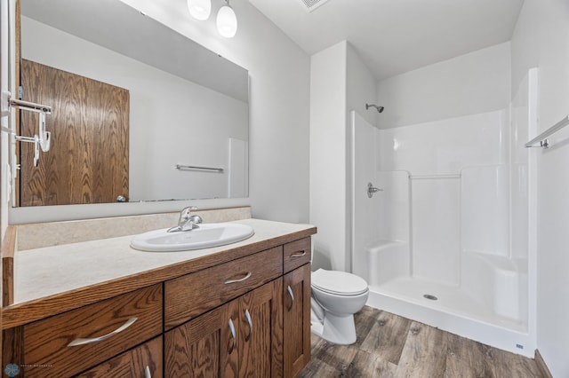 bathroom with wood finished floors, toilet, a shower, and vanity