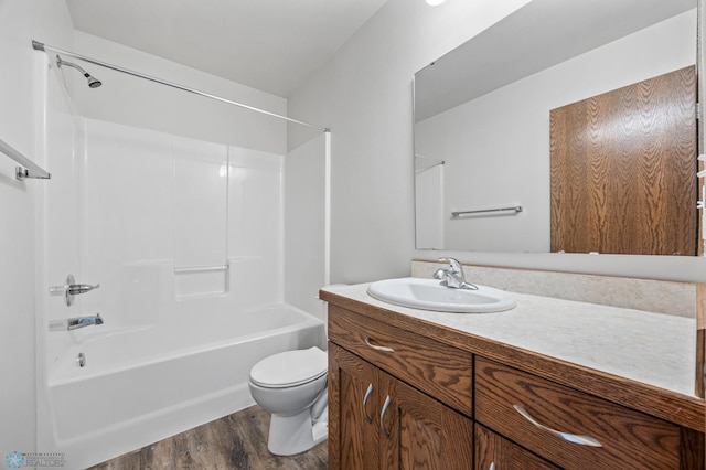 bathroom featuring wood finished floors, toilet, bathing tub / shower combination, and vanity
