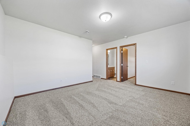 empty room featuring light colored carpet and baseboards