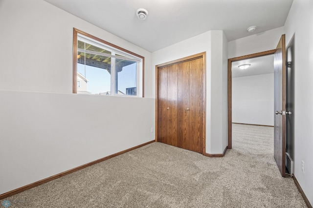 unfurnished bedroom with carpet floors, baseboards, and a closet