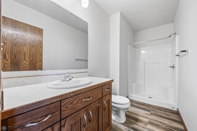 bathroom with wood finished floors, toilet, a shower, and vanity