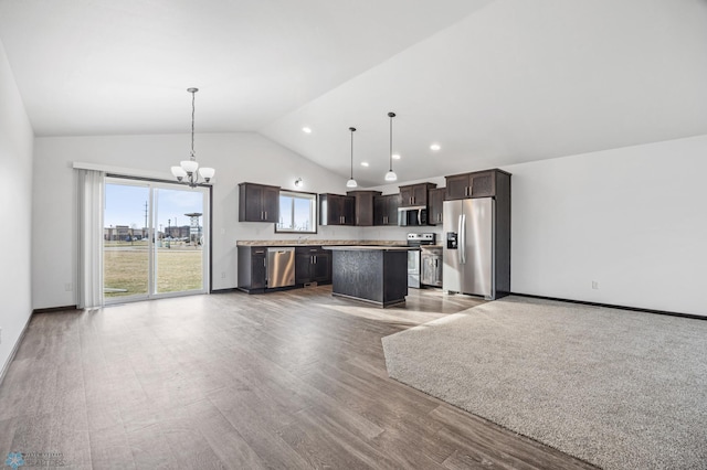 kitchen featuring appliances with stainless steel finishes, open floor plan, vaulted ceiling, dark brown cabinets, and a chandelier