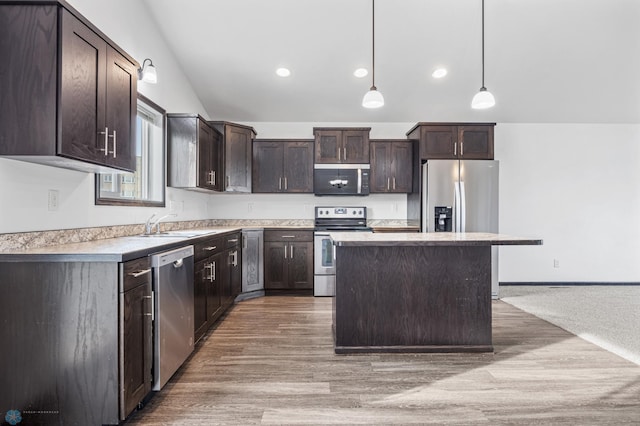 kitchen with appliances with stainless steel finishes, dark brown cabinetry, lofted ceiling, a center island, and light countertops