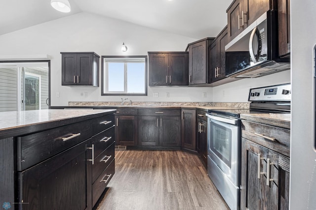kitchen with stainless steel range with electric cooktop, lofted ceiling, dark wood-type flooring, dark brown cabinets, and a sink