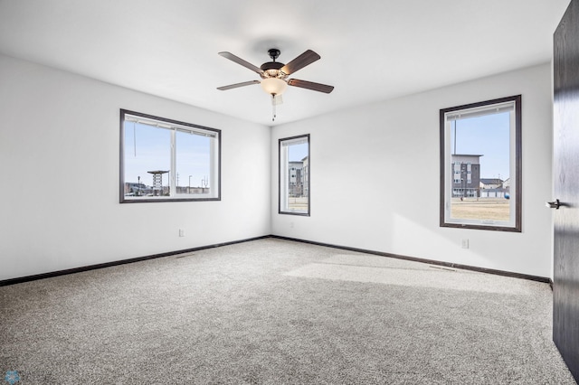 carpeted spare room with a ceiling fan and baseboards