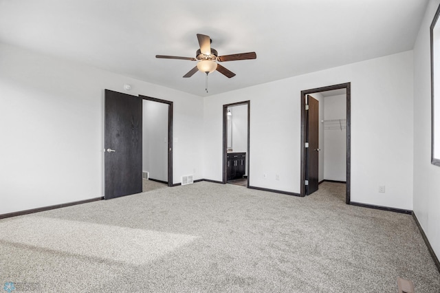 unfurnished bedroom featuring a spacious closet, a closet, carpet flooring, baseboards, and connected bathroom