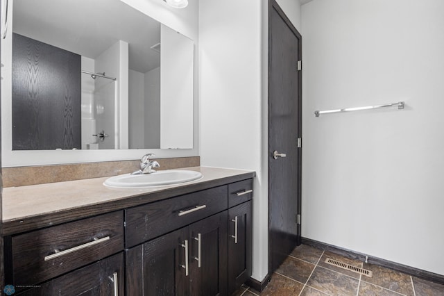 bathroom with vanity, baseboards, and a shower