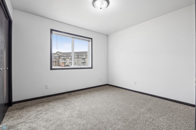 carpeted spare room featuring baseboards