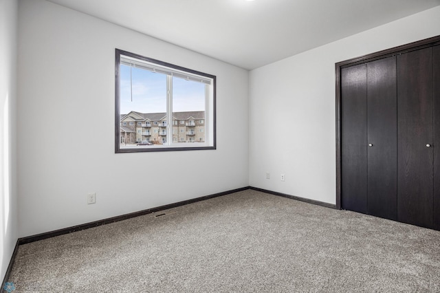 unfurnished bedroom featuring carpet flooring, a closet, and baseboards