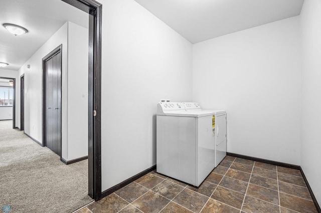 laundry area featuring independent washer and dryer, baseboards, and dark stone finish flooring