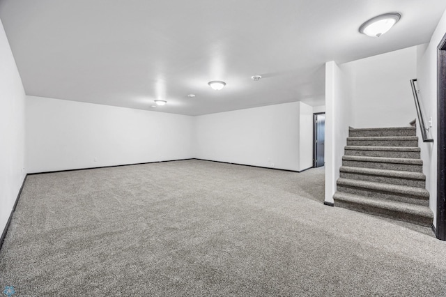 finished below grade area featuring stairway, carpet flooring, and baseboards