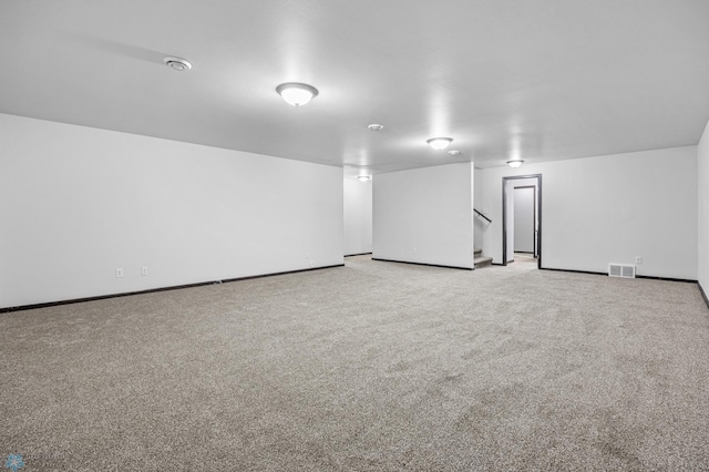 carpeted spare room featuring stairs and baseboards