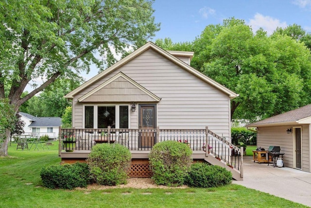rear view of house with a lawn, a wooden deck, and a patio area