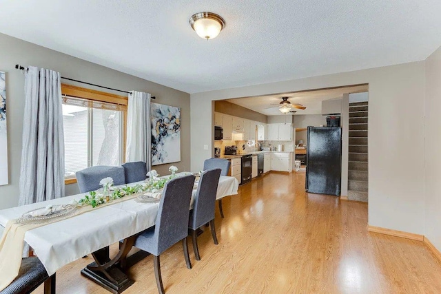 dining room featuring light wood-type flooring, ceiling fan, baseboards, and a textured ceiling
