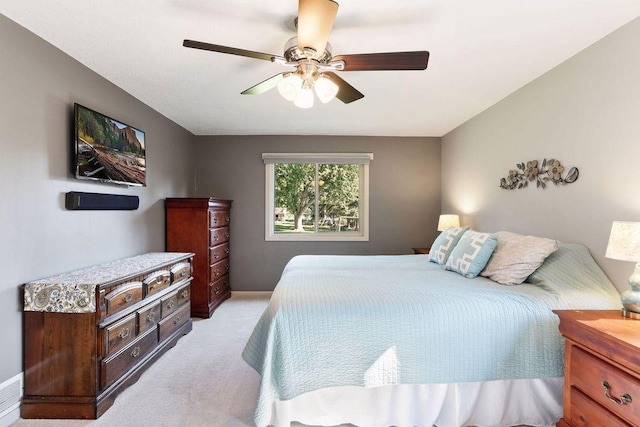 bedroom featuring light carpet, a ceiling fan, and baseboards