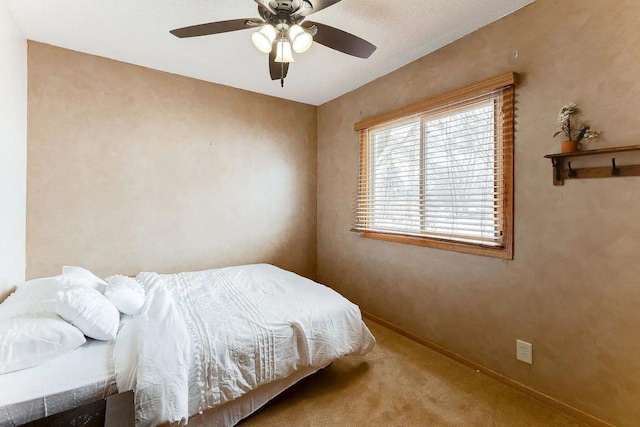 carpeted bedroom featuring baseboards and a ceiling fan