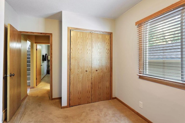 unfurnished bedroom featuring light colored carpet, a closet, and multiple windows