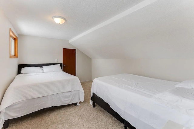 bedroom with light carpet, vaulted ceiling, and a textured ceiling