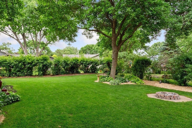 view of grassy yard featuring an outdoor fire pit