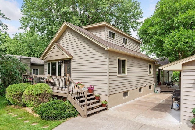 rear view of property with roof with shingles, a patio, and a deck