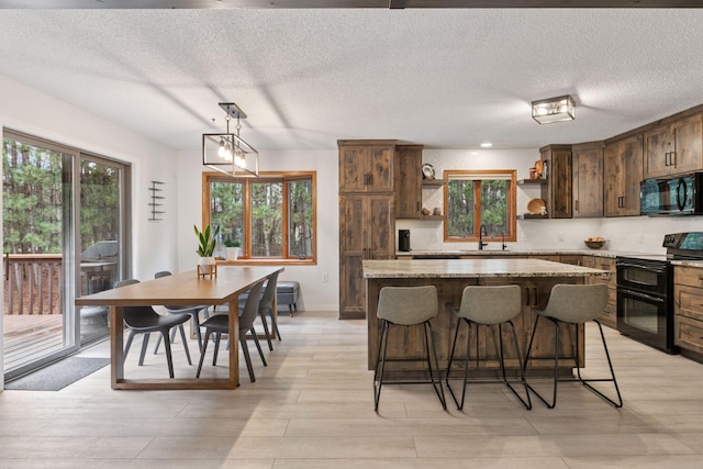 265 Red Pine Trl, Saint Joseph Twp, WI 54016 - kitchen with black appliances, open shelves, a sink, a center island, and a breakfast bar area