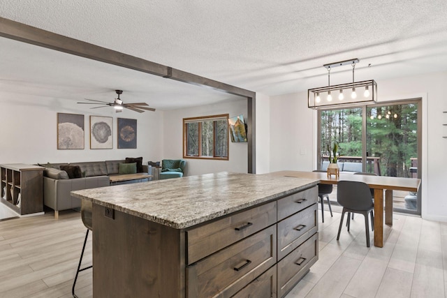 265 Red Pine Trl, Saint Joseph Twp, WI 54016 - kitchen with a textured ceiling, hanging light fixtures, light wood-type flooring, a kitchen island, and a kitchen bar