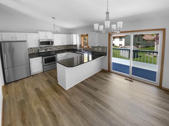 4984 Park Dr, Savage, MN 55378 - kitchen with stainless steel appliances, a chandelier, white cabinets, dark countertops, and backsplash