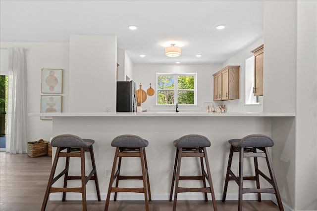 3822 Northern Ave, Spring Park, MN 55384 - kitchen with freestanding refrigerator, a kitchen bar, a peninsula, wood finished floors, and recessed lighting