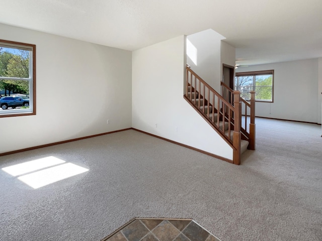 unfurnished living room featuring carpet flooring, stairs, and baseboards