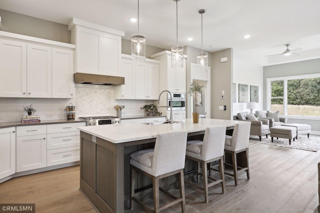 4104 Osprey Ct, Prior Lake, MN 55372 - kitchen with a sink, backsplash, a kitchen island with sink, a breakfast bar area, and white cabinets