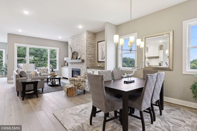 4104 Osprey Ct, Prior Lake, MN 55372 - dining room featuring a stone fireplace, wood finished floors, a chandelier, recessed lighting, and baseboards
